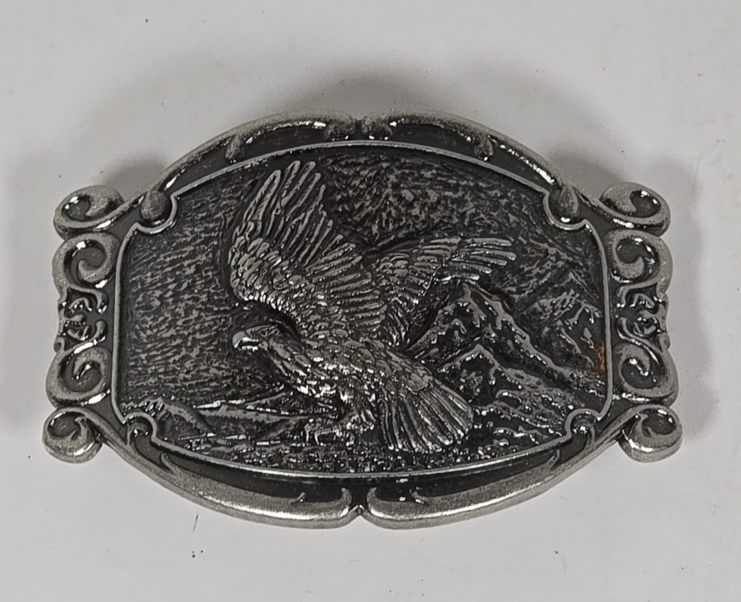 Silver Tone Belt Buckle With Eagle In Flight Against A Mountain Backdrop
