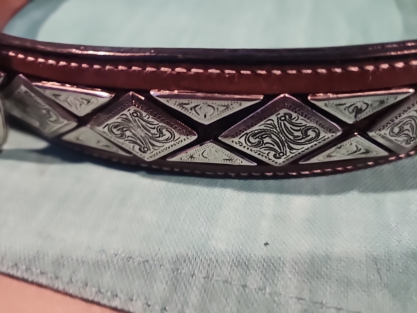 Western belt in basketweave texture featuring floral-engraved buckle in…