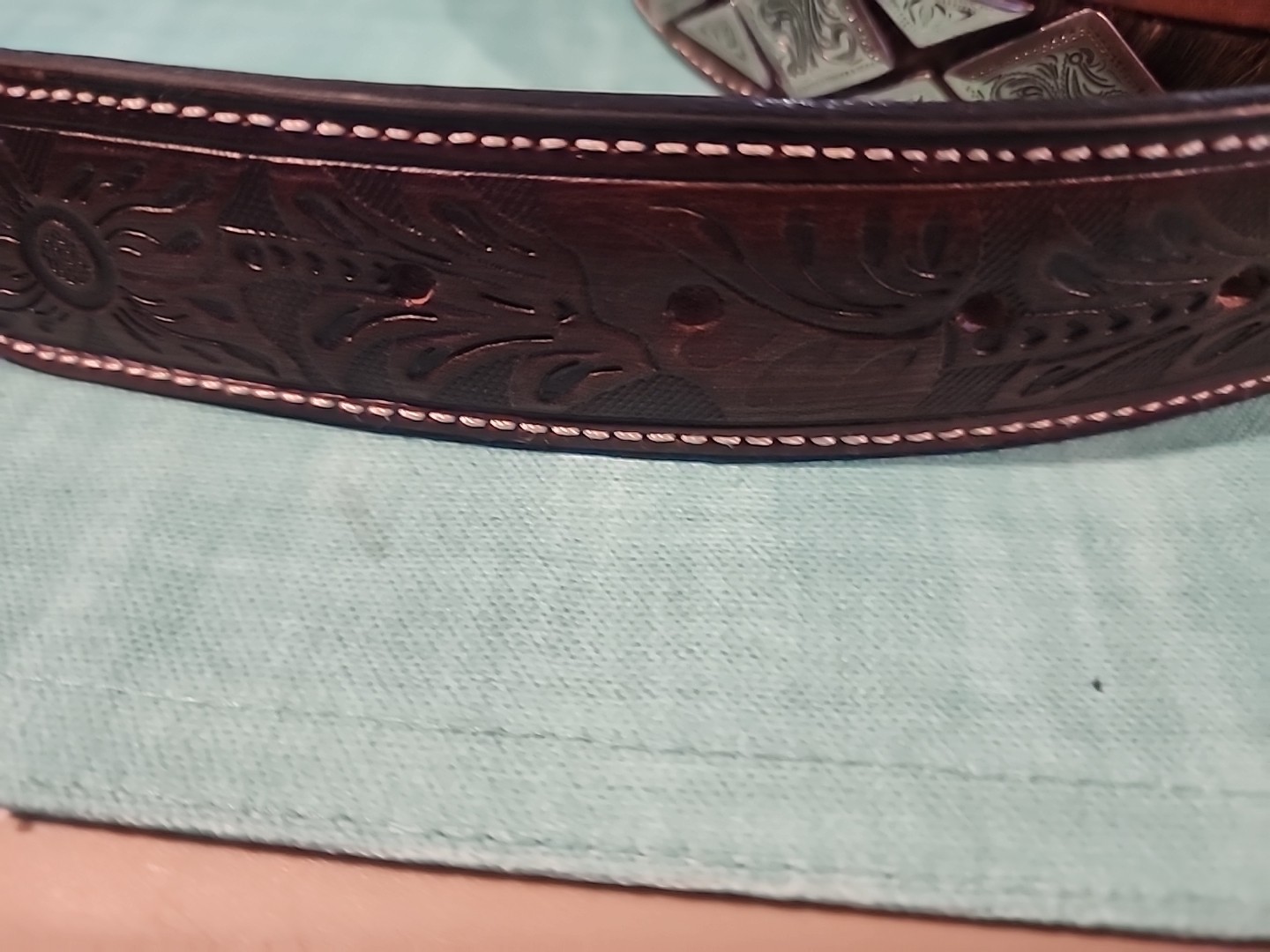 Western belt in basketweave texture featuring floral-engraved buckle in…