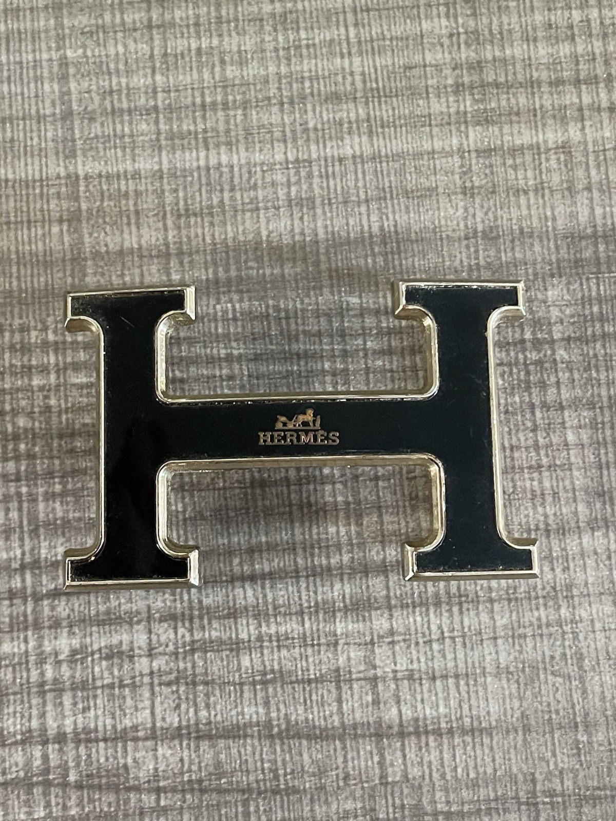 This is a gold-plated Hermès H Quizz belt buckle featuring a black lacquer inlay