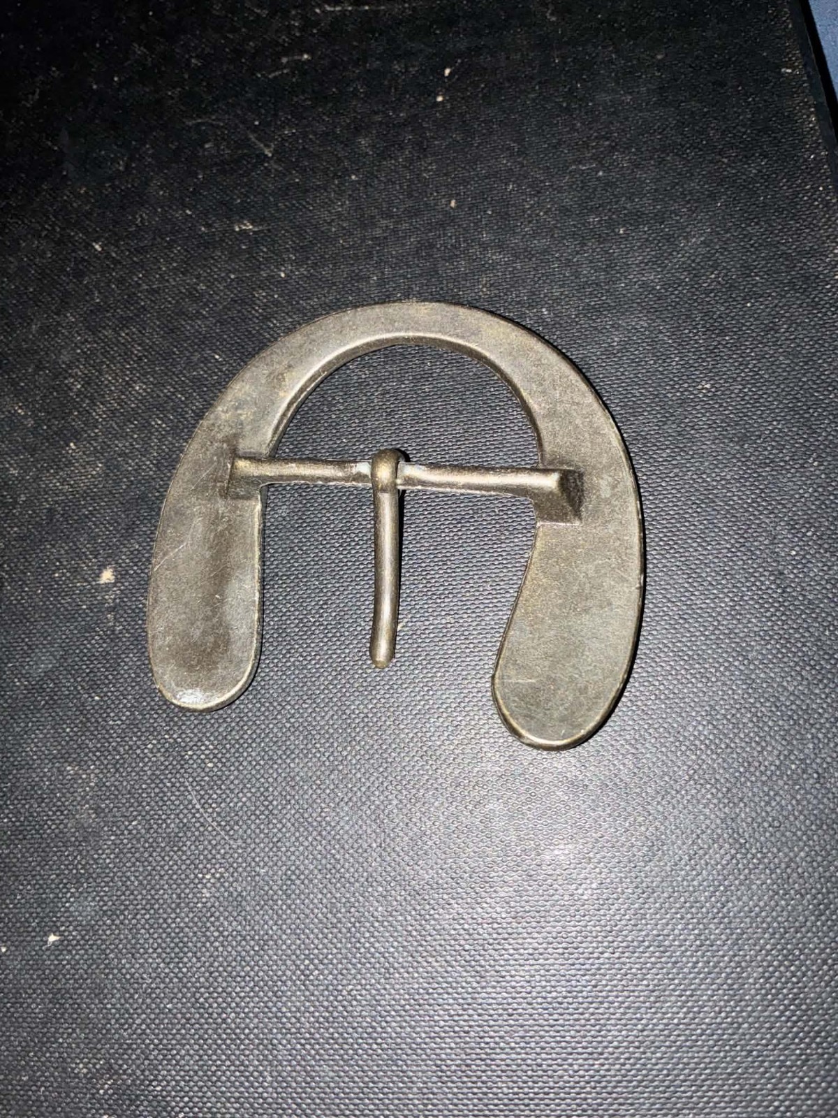 This vintage-style, handmade steel belt buckle is shaped like a horseshoe