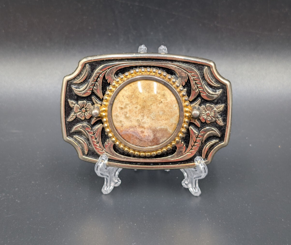 Black in lay silver toned belt buckle with marbled faux stone outlined is raised