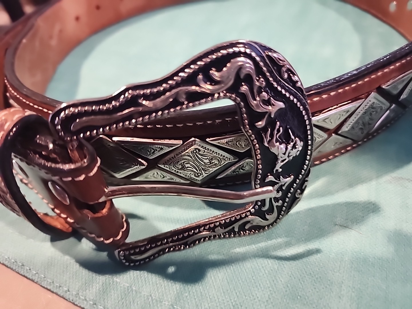 Western belt in basketweave texture featuring floral-engraved buckle in…