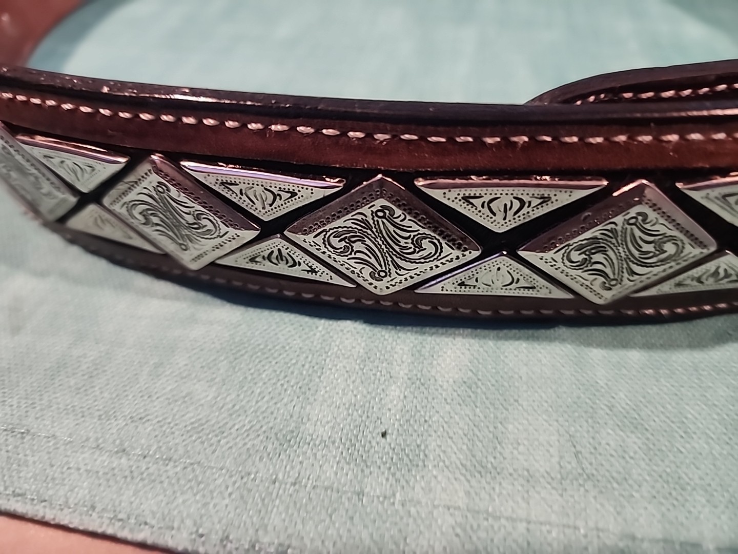 Western belt in basketweave texture featuring floral-engraved buckle in…