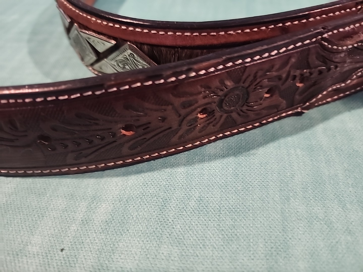 Western belt in basketweave texture featuring floral-engraved buckle in…