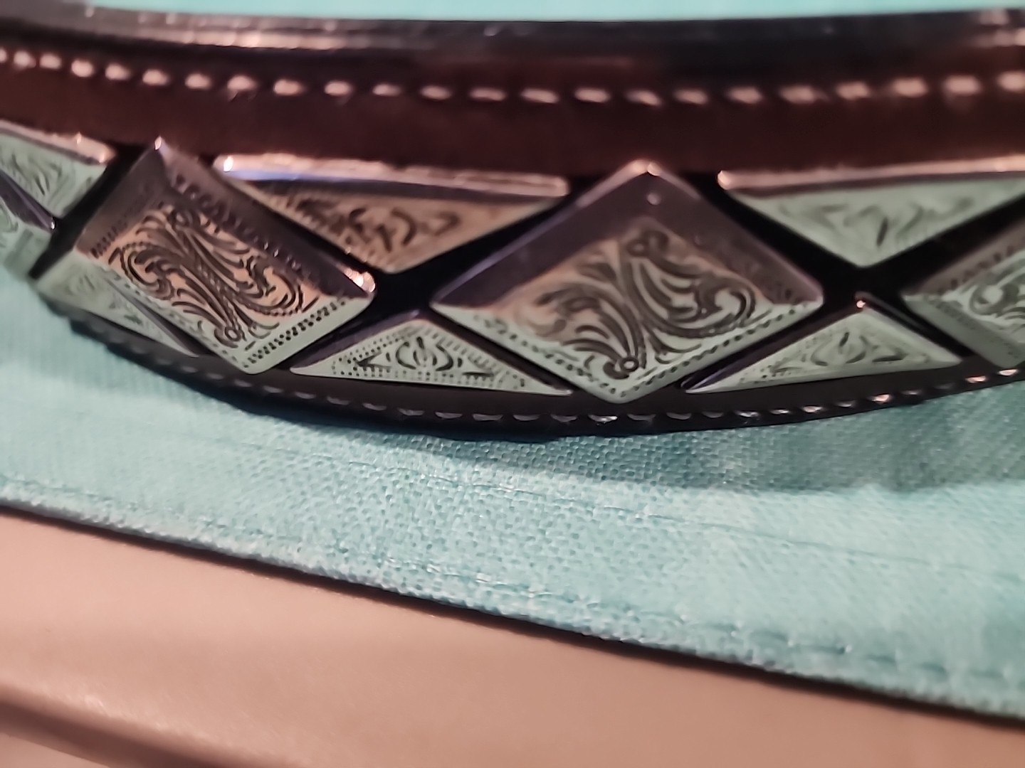 Western belt in basketweave texture featuring floral-engraved buckle in…