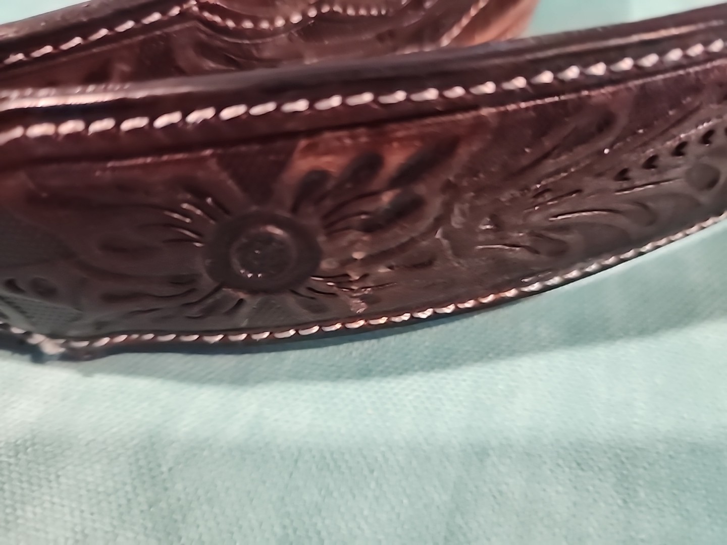 Western belt in basketweave texture featuring floral-engraved buckle in…