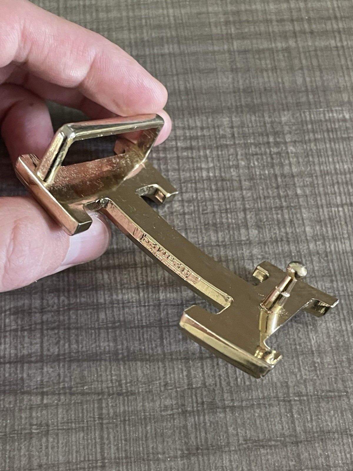 This is a gold-plated Hermès H Quizz belt buckle featuring a black lacquer inlay