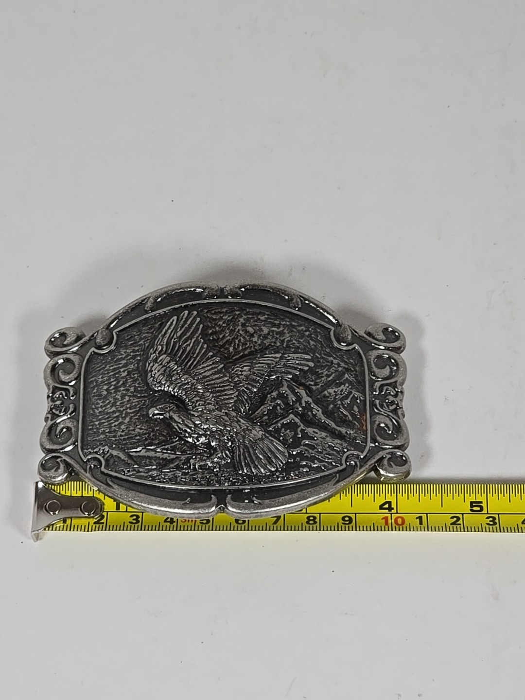 Silver Tone Belt Buckle With Eagle In Flight Against A Mountain Backdrop