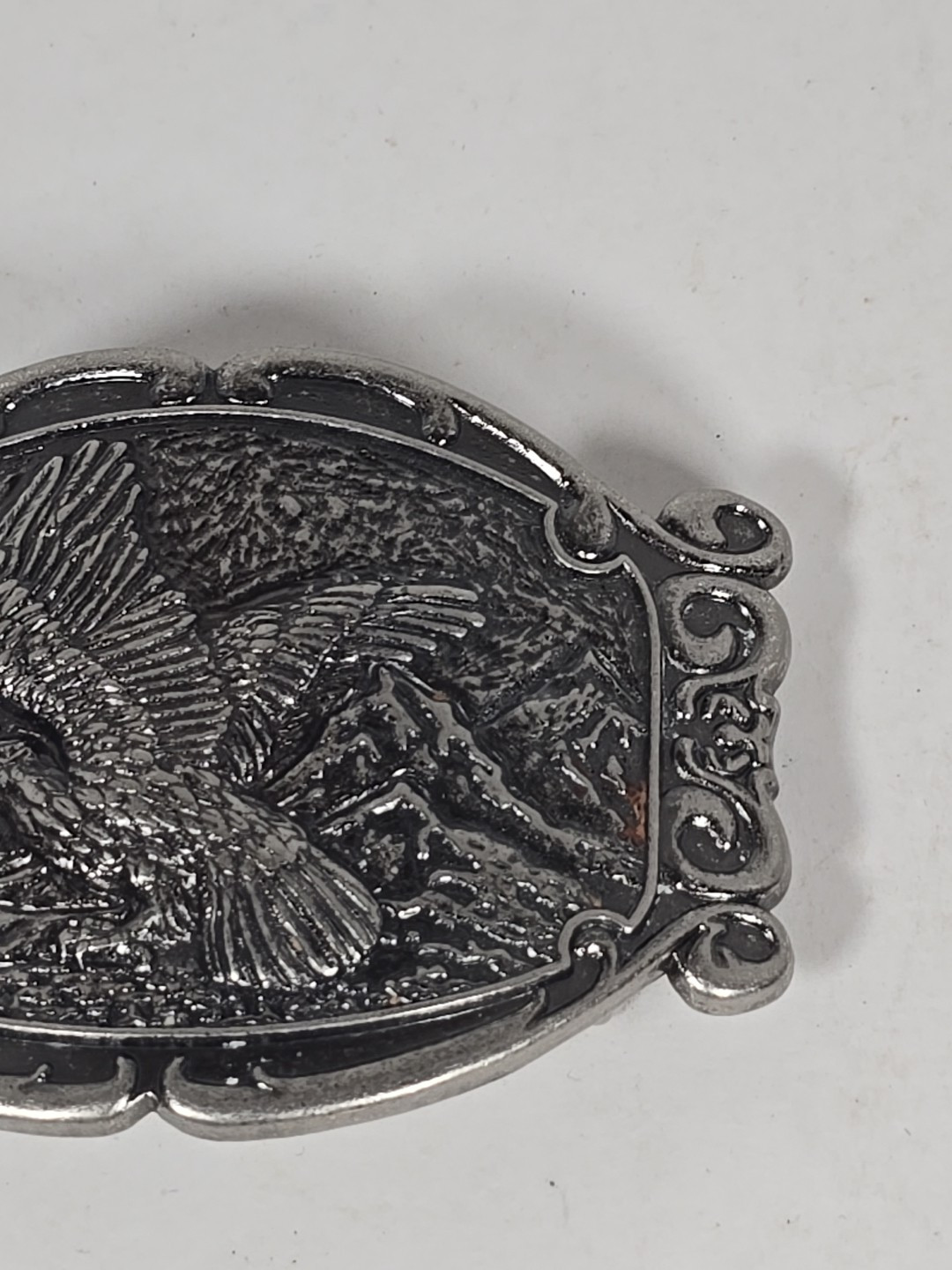 Silver Tone Belt Buckle With Eagle In Flight Against A Mountain Backdrop