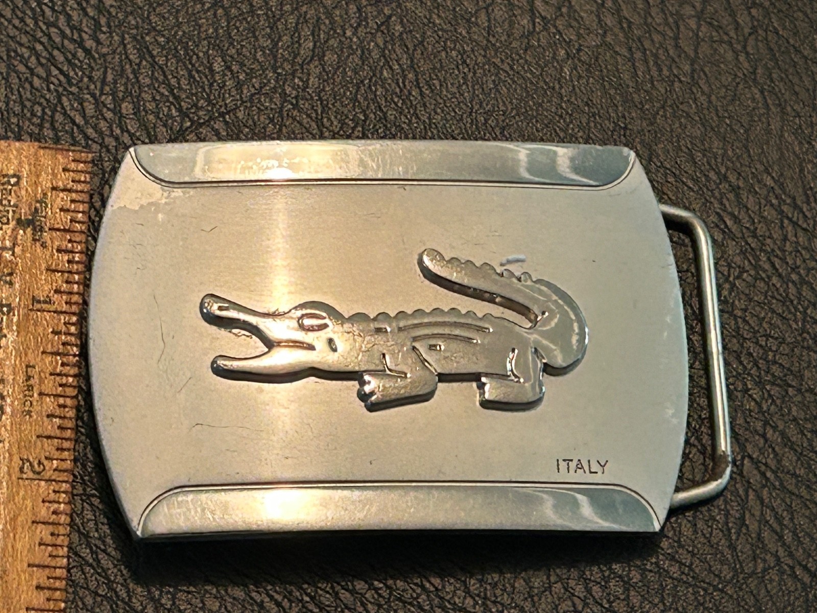 Silver-toned metal belt buckle, embossed crocodile logo and « ITALY »