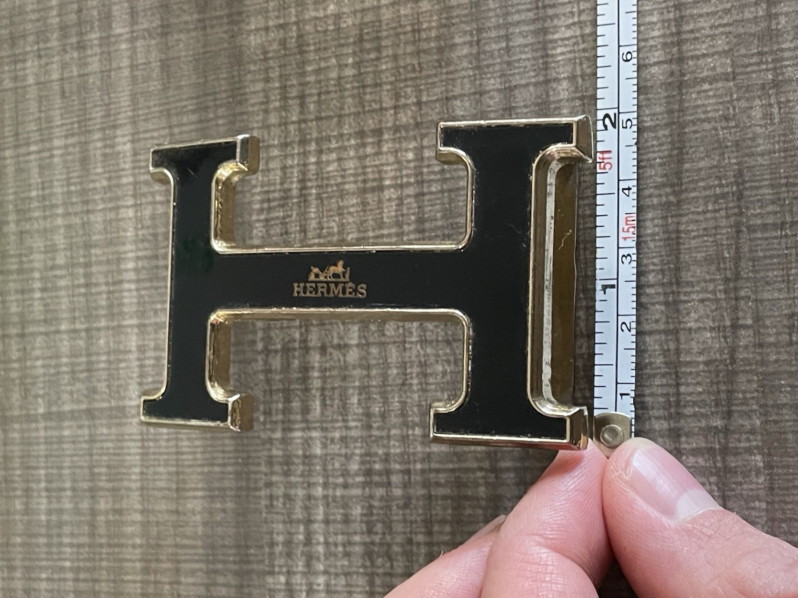 This is a gold-plated Hermès H Quizz belt buckle featuring a black lacquer inlay