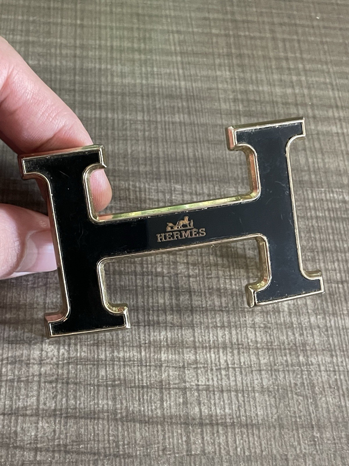 This is a gold-plated Hermès H Quizz belt buckle featuring a black lacquer inlay