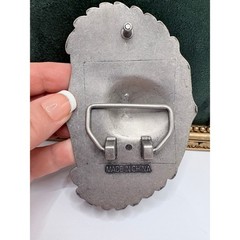 Silver-tone belt buckle featuring a skull with wings and roses