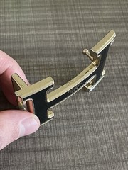 This is a gold-plated Hermès H Quizz belt buckle featuring a black lacquer inlay