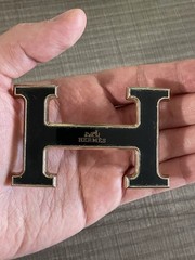 This is a gold-plated Hermès H Quizz belt buckle featuring a black lacquer inlay