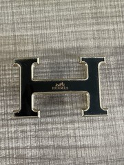 This is a gold-plated Hermès H Quizz belt buckle featuring a black lacquer inlay