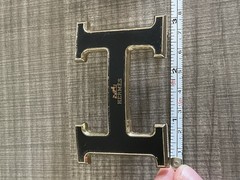 This is a gold-plated Hermès H Quizz belt buckle featuring a black lacquer inlay