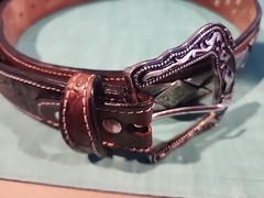 Western belt in basketweave texture featuring floral-engraved buckle in…