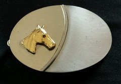SIMPLE SHINY SILVER TONED OVAL WESTERN BELT BUCKLE WITH A 3D GOLD COLORED HORSE