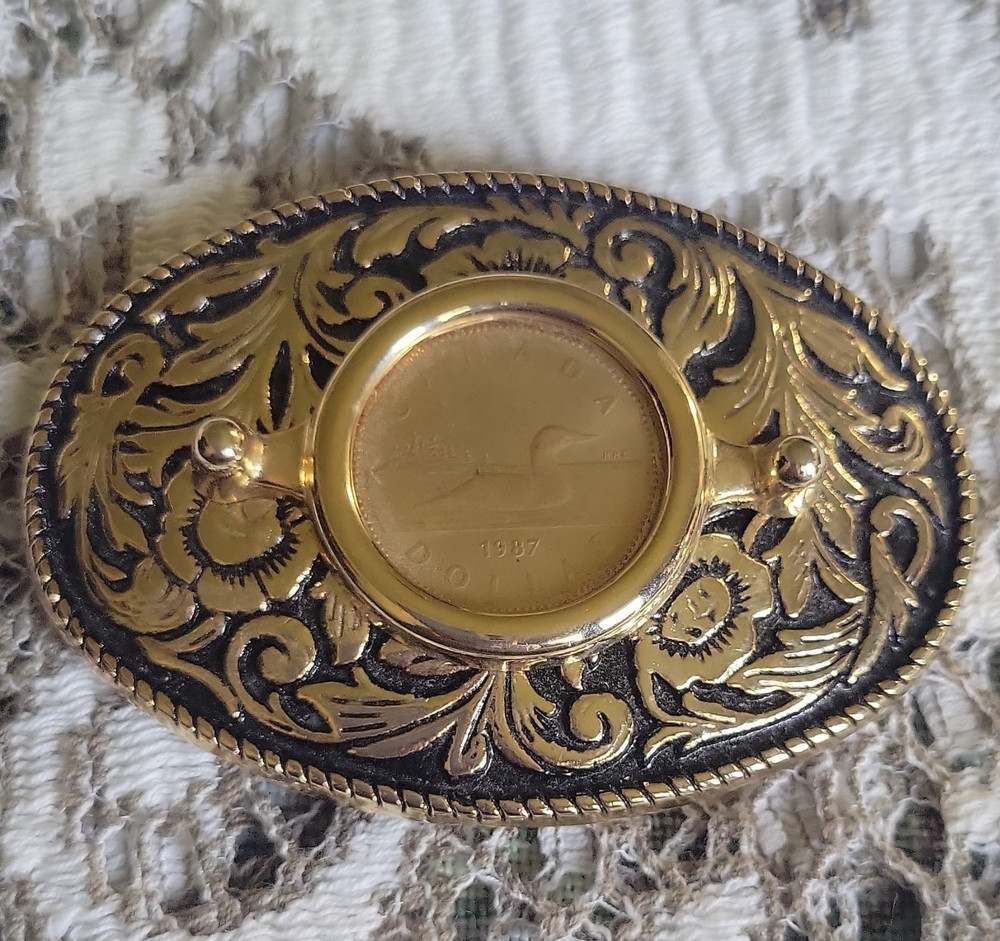 Vntage, gold-toned oval belt buckle features 1987 Canadian One Dollar Coin