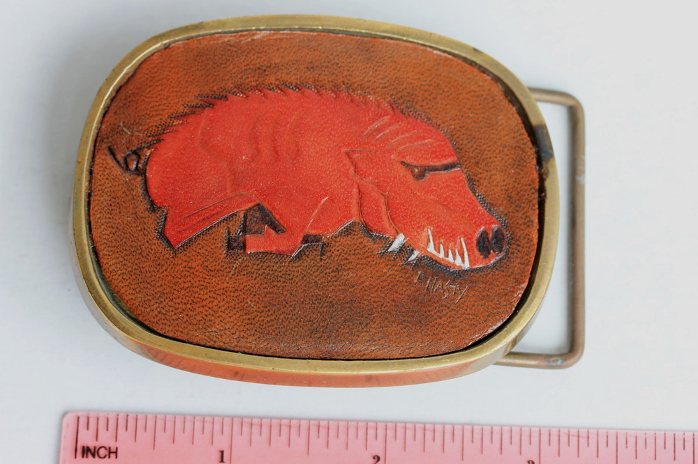 Vintage solid brass belt buckle with leather hog insert, artist signed C. Hasty