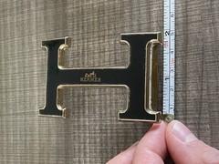 This is a gold-plated Hermès H Quizz belt buckle featuring a black lacquer inlay