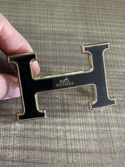 This is a gold-plated Hermès H Quizz belt buckle featuring a black lacquer inlay