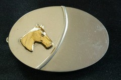 SIMPLE SHINY SILVER TONED OVAL WESTERN BELT BUCKLE WITH A 3D GOLD COLORED HORSE